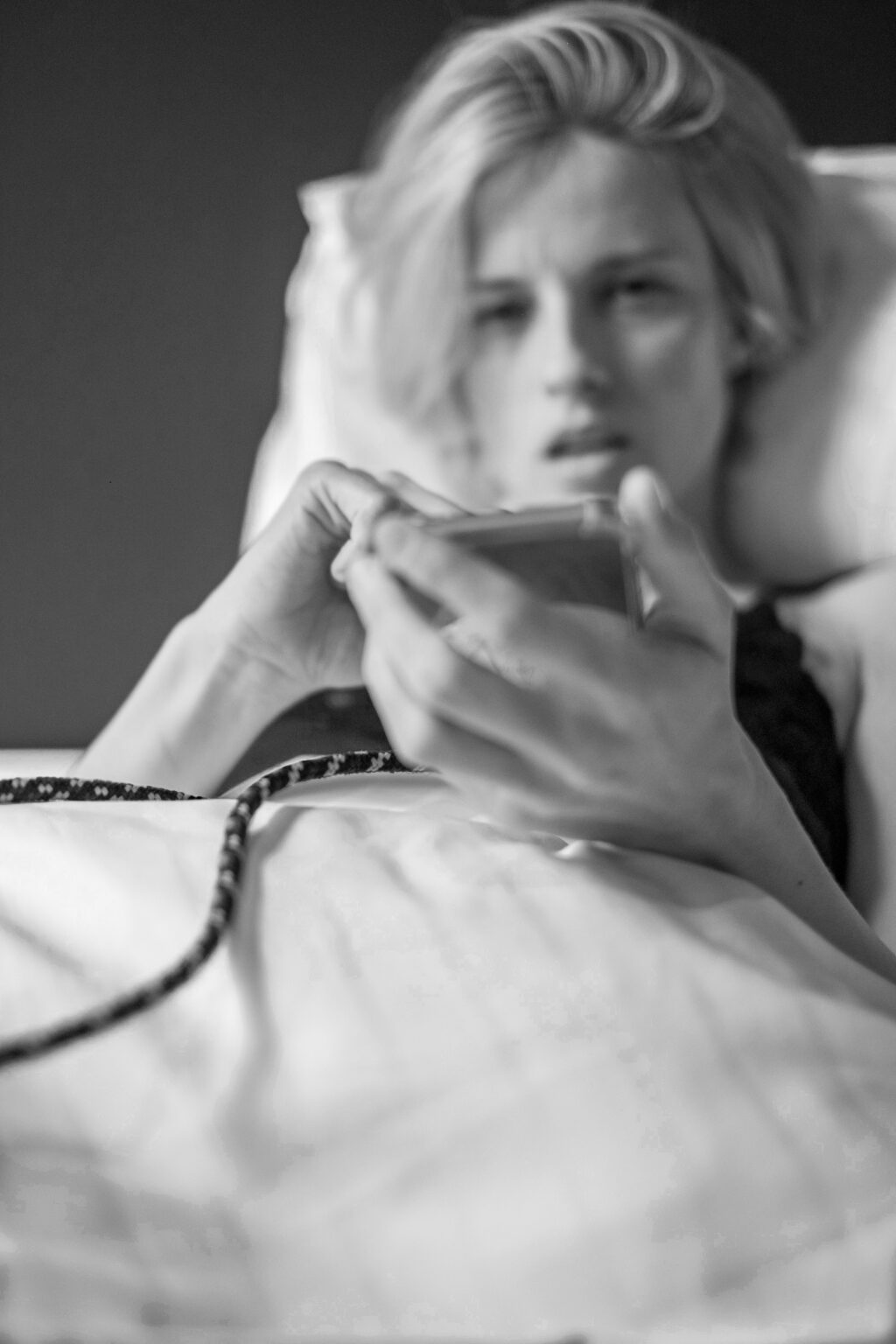 Frau mit Handy im Hotelbett in schwarz weiß