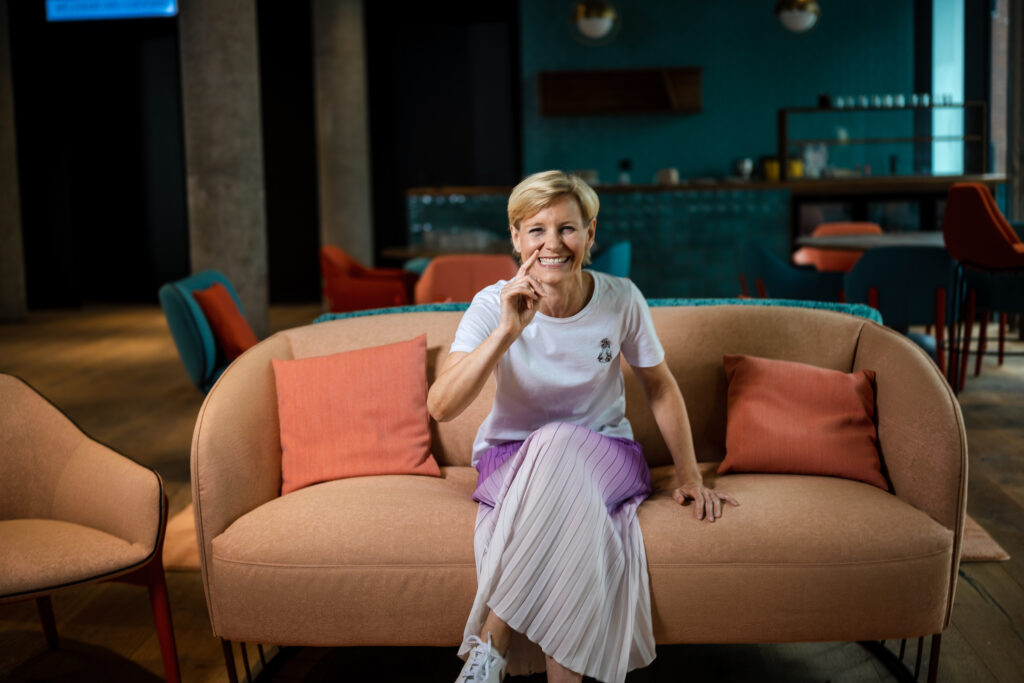 Gut gelaunte Frau sitzt auf dem Sofa der Lobby im Hotel International