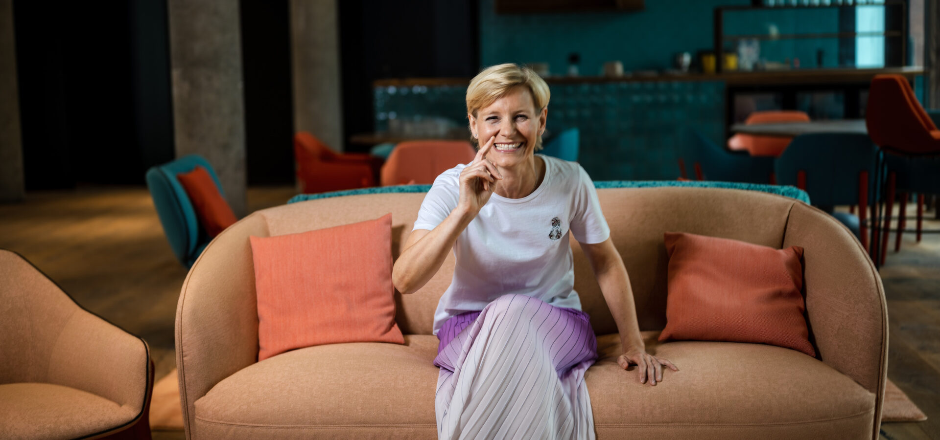 Gut gelaunte Frau sitzt auf dem Sofa der Lobby im Hotel International