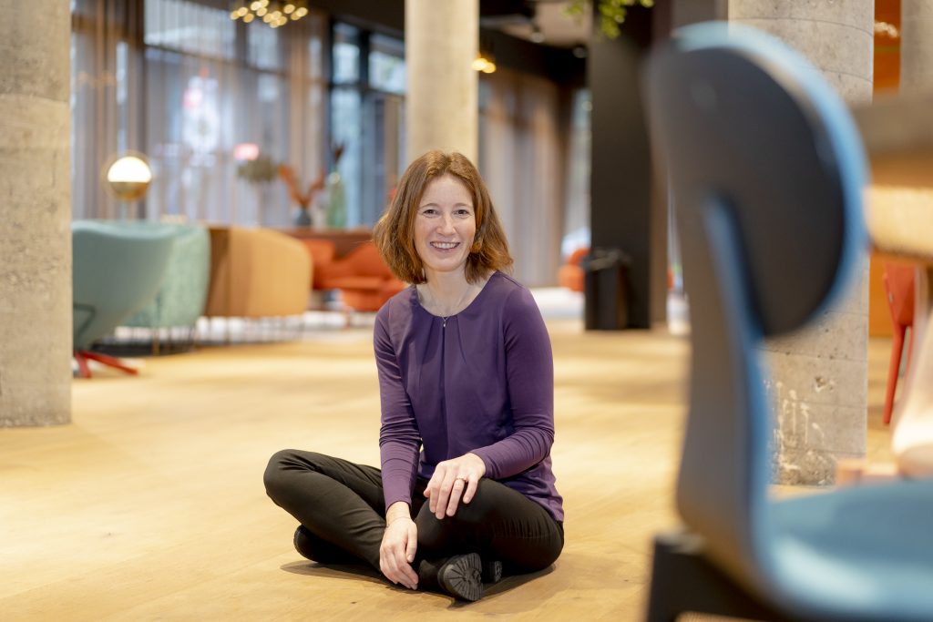 Sabine Schrempp sitzt auf dem Boden und lächelt