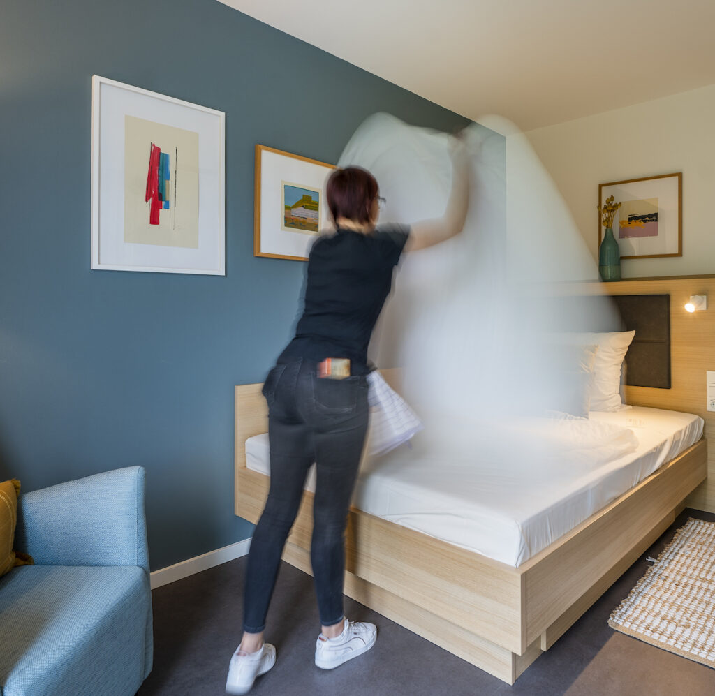 Frau macht das Bett im Zimmer des KONCEPT HOTELS